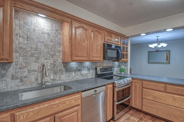 kitchen with sink, a chandelier, decorative backsplash, appliances with stainless steel finishes, and hardwood / wood-style flooring