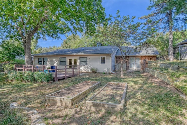 rear view of house with a garden, fence, a deck, and a lawn