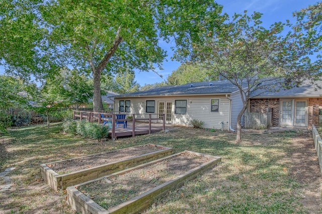 rear view of house with a yard, a vegetable garden, and a wooden deck