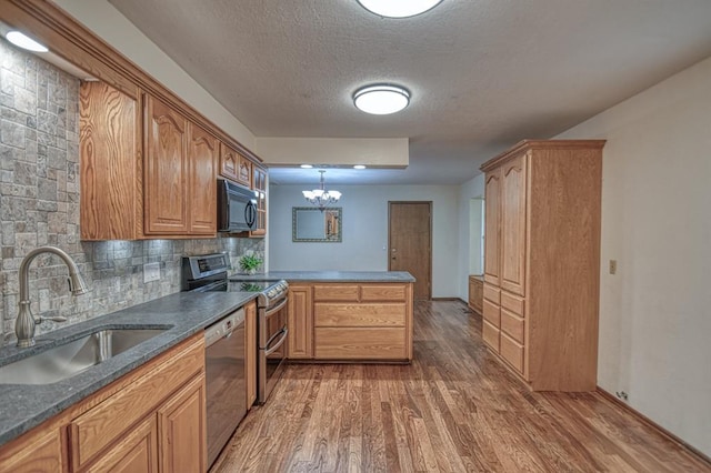 kitchen with a peninsula, stainless steel appliances, a sink, and wood finished floors