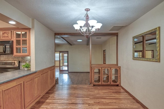 interior space featuring light wood-style floors, visible vents, a notable chandelier, and a textured ceiling