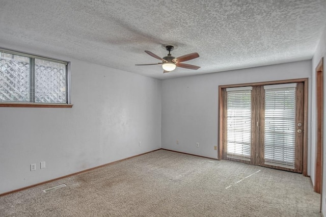 carpeted spare room with visible vents, ceiling fan, a textured ceiling, and baseboards