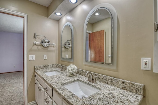 bathroom with double vanity, a sink, and baseboards