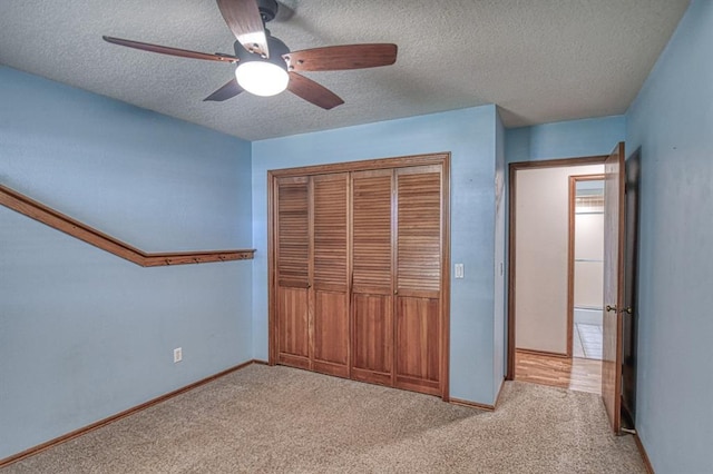 unfurnished bedroom featuring baseboards, a ceiling fan, a textured ceiling, carpet flooring, and a closet