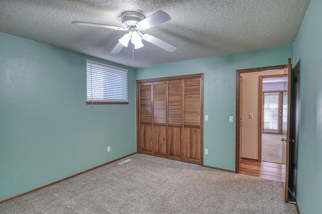 unfurnished bedroom with ceiling fan, a textured ceiling, carpet floors, visible vents, and a closet