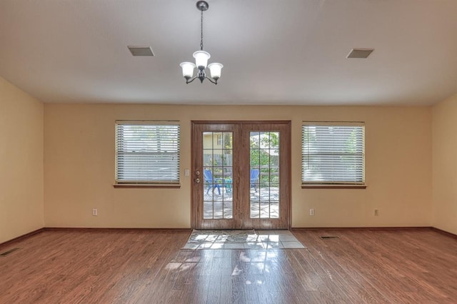 entryway featuring a chandelier, wood finished floors, visible vents, and baseboards