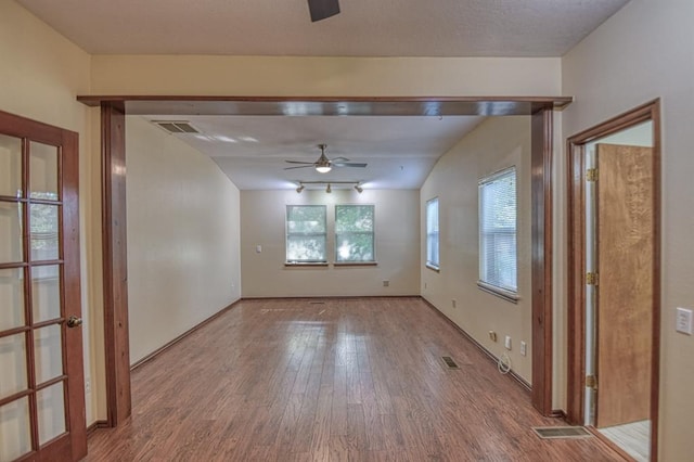 unfurnished room with visible vents, ceiling fan, and wood finished floors