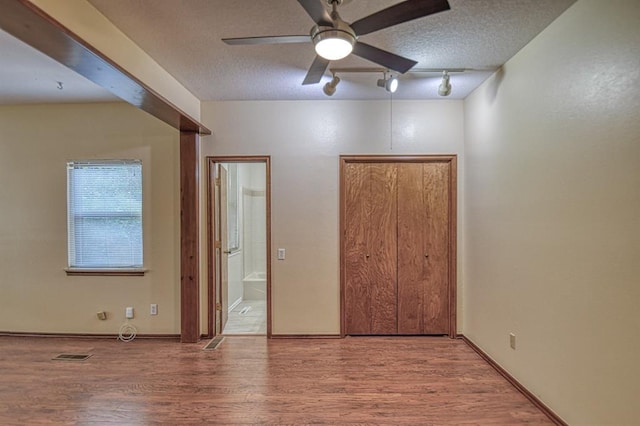 unfurnished room with a ceiling fan, visible vents, a textured ceiling, and wood finished floors