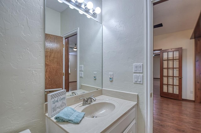 bathroom with a textured wall, vanity, and wood finished floors