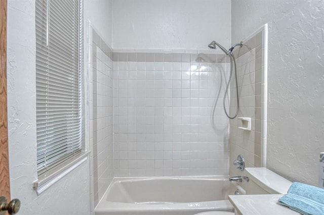 full bath featuring washtub / shower combination, a textured wall, vanity, and toilet