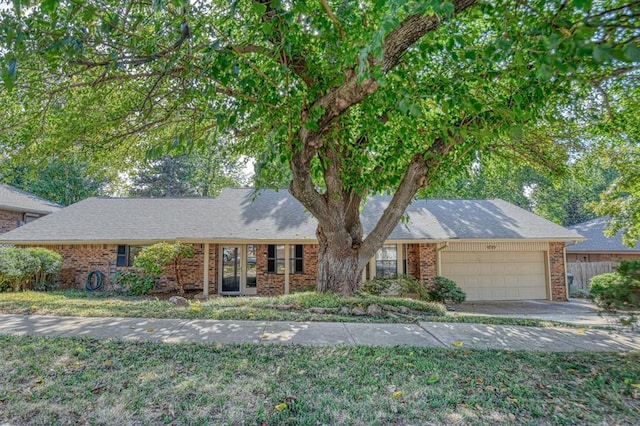 single story home featuring brick siding, roof with shingles, an attached garage, and fence