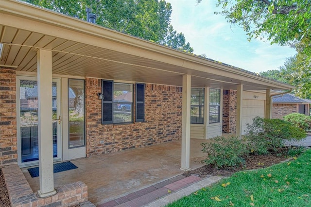 entrance to property featuring a porch, brick siding, and an attached garage