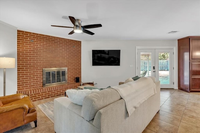 living room with ceiling fan, french doors, a brick fireplace, light tile patterned floors, and ornamental molding