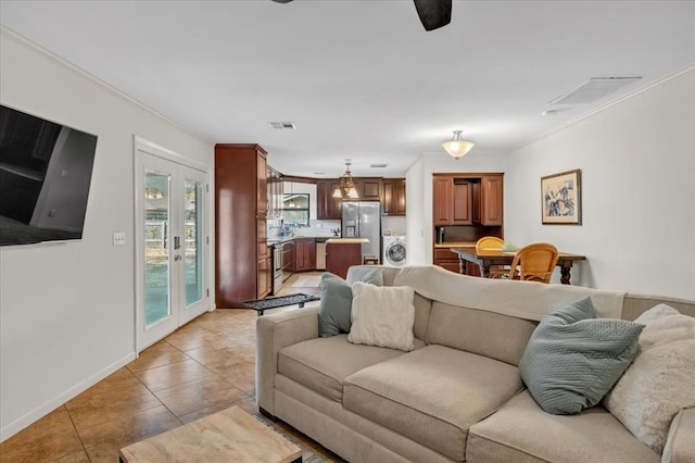 living room featuring tile patterned flooring, washer / dryer, french doors, and crown molding