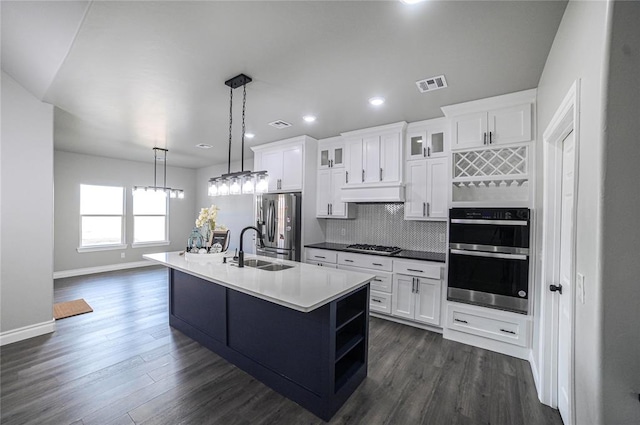 kitchen with white cabinetry, sink, stainless steel appliances, an island with sink, and decorative light fixtures