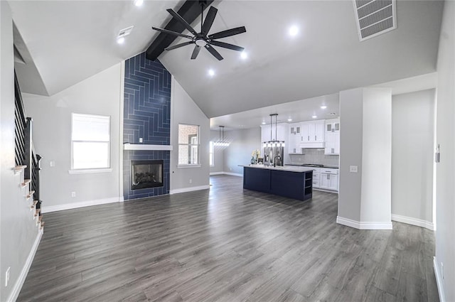 unfurnished living room featuring beam ceiling, ceiling fan, sink, dark hardwood / wood-style floors, and a fireplace