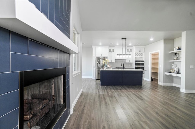 unfurnished living room with dark hardwood / wood-style flooring, built in features, sink, and a tile fireplace