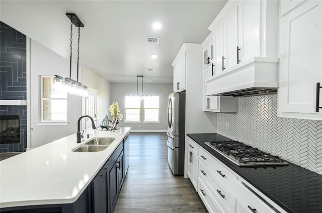 kitchen featuring a kitchen island with sink, sink, hanging light fixtures, appliances with stainless steel finishes, and tasteful backsplash