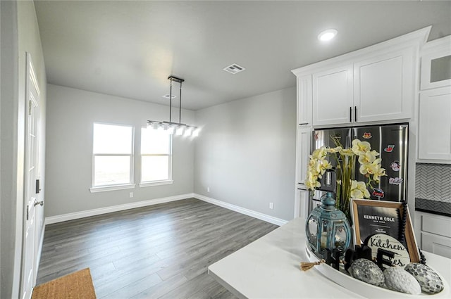 kitchen featuring white cabinets, hanging light fixtures, dark hardwood / wood-style floors, stainless steel fridge, and tasteful backsplash