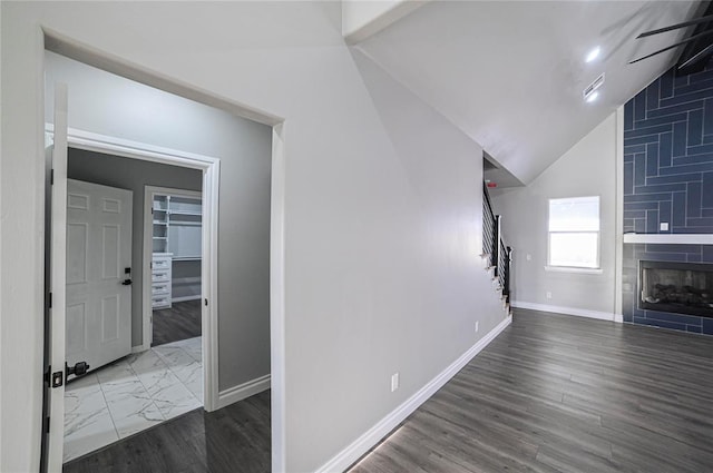 entrance foyer featuring ceiling fan, wood-type flooring, a tile fireplace, and vaulted ceiling