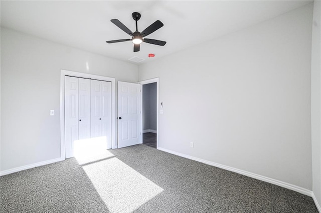 unfurnished bedroom featuring ceiling fan, dark carpet, and a closet