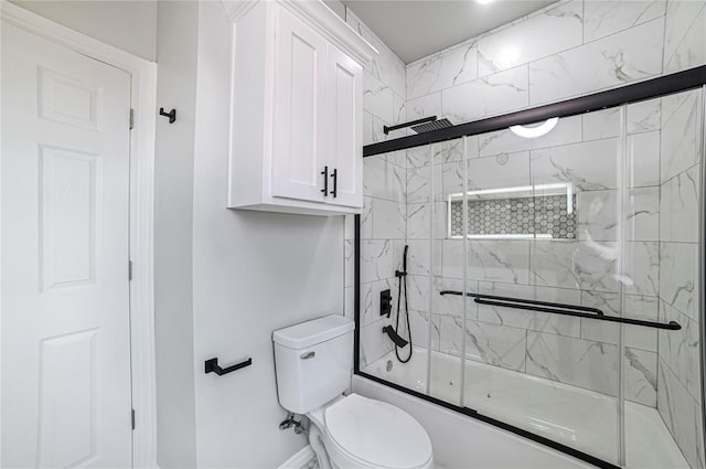 bathroom featuring toilet and shower / bath combination with glass door