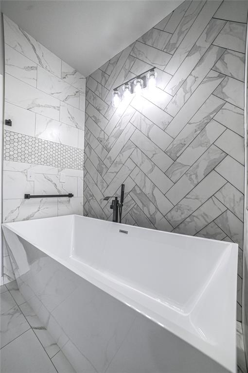 bathroom featuring a bath and tile walls