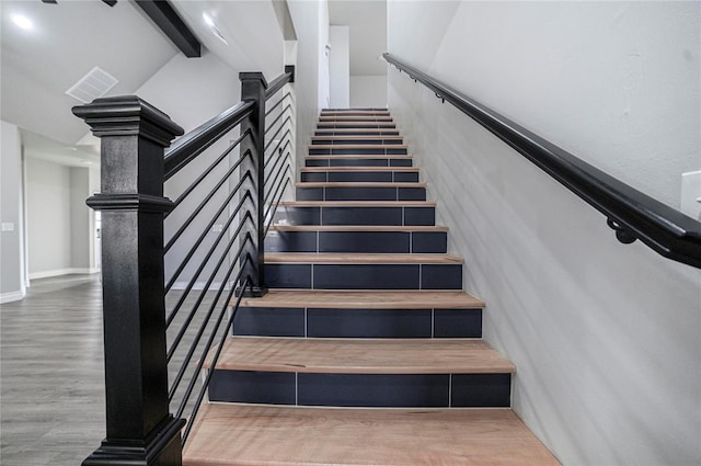 staircase with beamed ceiling and wood-type flooring