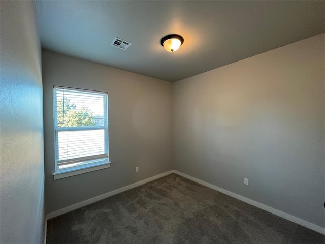 unfurnished room with dark colored carpet