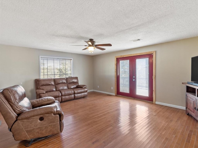 living room with ceiling fan, wood-type flooring, a textured ceiling, and french doors