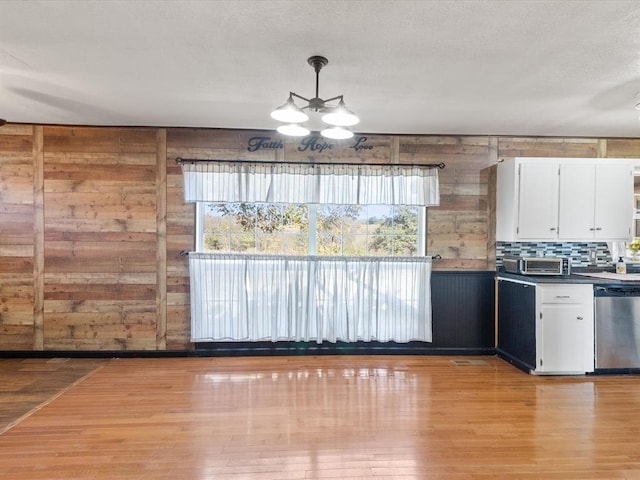 kitchen with white cabinetry, stainless steel dishwasher, backsplash, pendant lighting, and light wood-type flooring