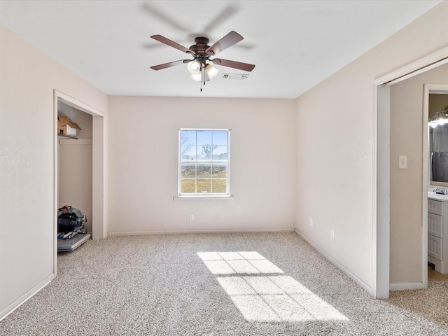 unfurnished bedroom with ceiling fan, ensuite bath, light carpet, and a closet