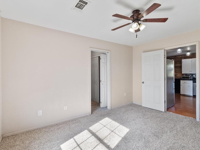 unfurnished bedroom with ceiling fan, carpet floors, and stainless steel refrigerator