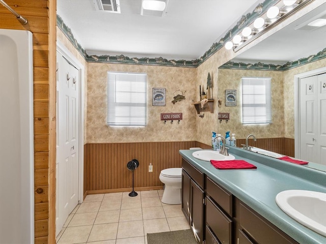 bathroom with tile patterned flooring, vanity, toilet, and wooden walls