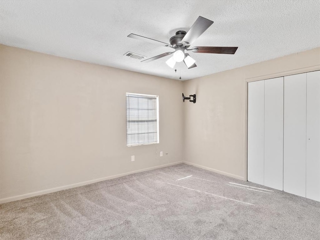 unfurnished bedroom with baseboards, ceiling fan, carpet flooring, a closet, and a textured ceiling