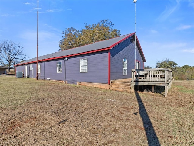 view of home's exterior featuring metal roof, a lawn, central AC unit, and a deck