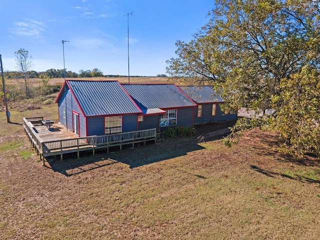 exterior space with a wooden deck, a front lawn, and metal roof