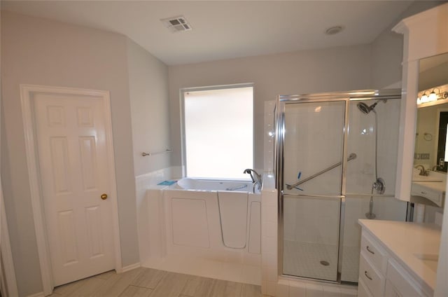 bathroom featuring vanity and independent shower and bath