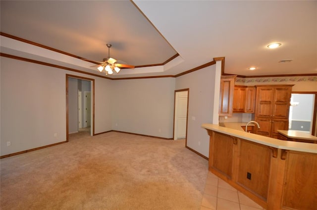 kitchen with light carpet, crown molding, ceiling fan, a kitchen bar, and kitchen peninsula