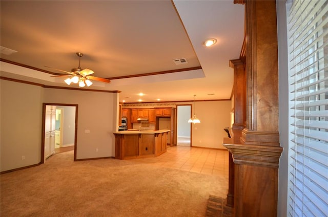 unfurnished living room featuring ceiling fan, light colored carpet, ornamental molding, and a tray ceiling