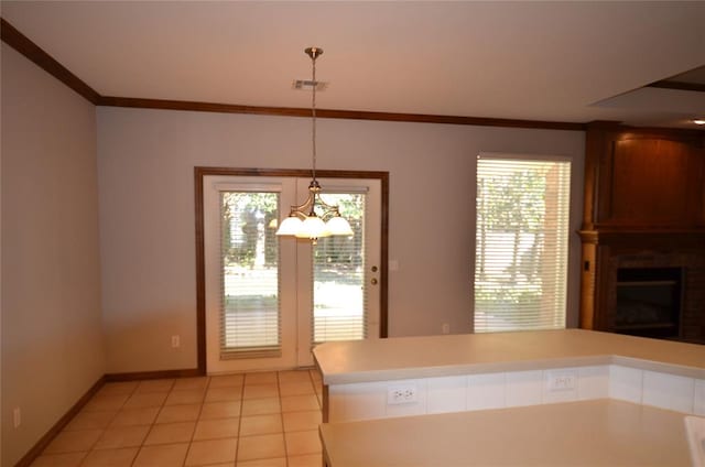 kitchen featuring an inviting chandelier, crown molding, pendant lighting, a fireplace, and light tile patterned floors