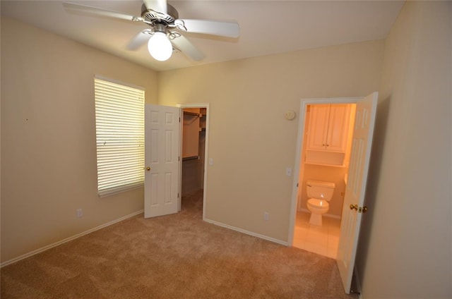 unfurnished bedroom featuring a spacious closet, a closet, ceiling fan, and light carpet