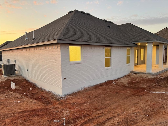 property exterior at dusk featuring a patio area and central air condition unit