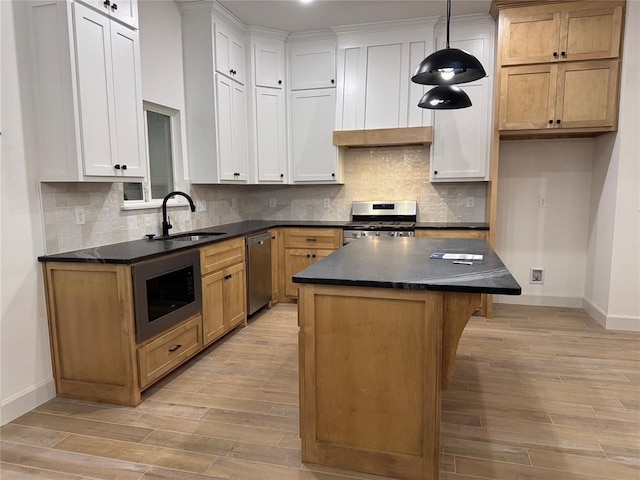 kitchen with stainless steel appliances, sink, a kitchen island, and white cabinets