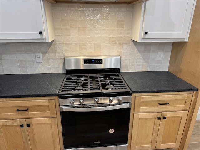 kitchen with white cabinetry, stainless steel gas range oven, and backsplash