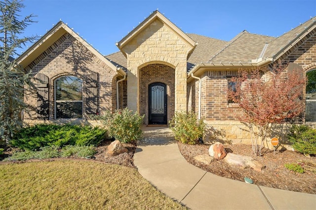 view of front of home with stone siding, brick siding, and a shingled roof