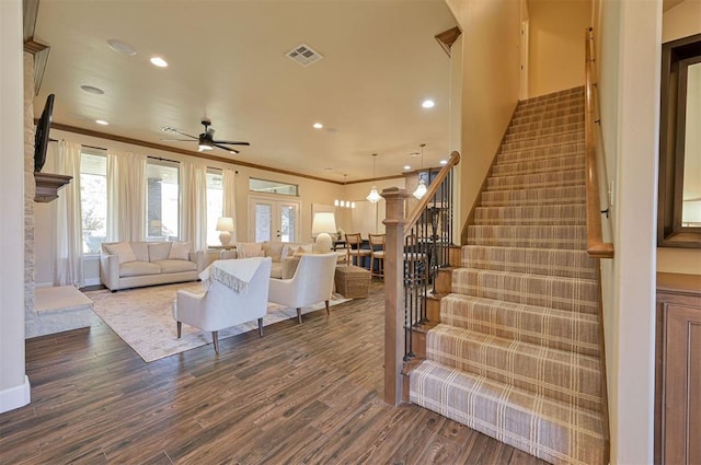 living area with visible vents, ornamental molding, dark wood finished floors, french doors, and stairway