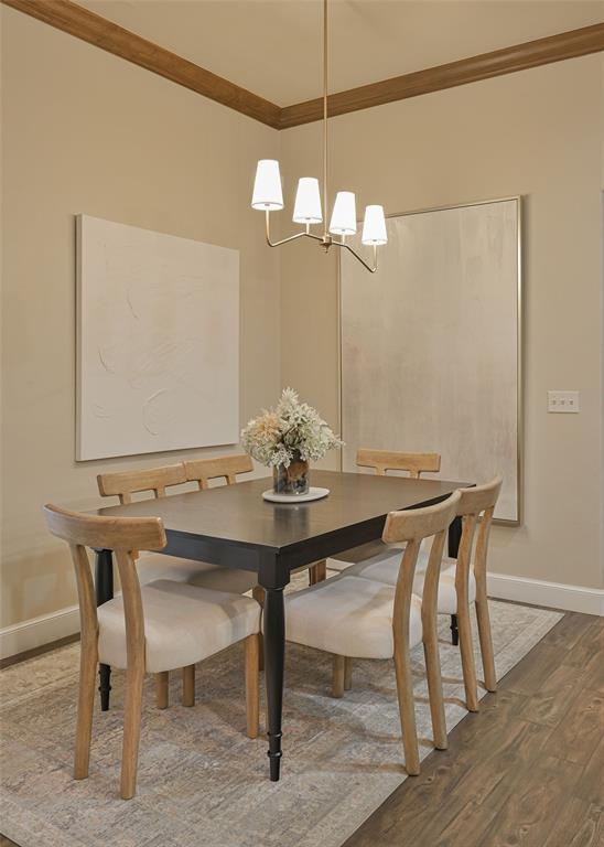 dining area with crown molding, wood finished floors, baseboards, and a chandelier