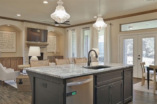 kitchen featuring ornamental molding, dishwasher, a fireplace, and a sink