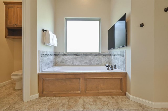 full bathroom featuring baseboards, toilet, and a bath